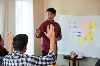 Sıradan ekose gömlek giyen genç Asyalı erkeklerin eli konferanstaki meslektaşlarından başarılı bir iş yürütme konusunda geri bildirim istiyor. Takım çalışması iş toplantısı