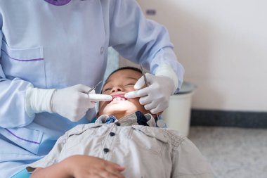 Diş hekiminin elleri diş aletini tutuyor. Hastanedeki dişçi koltuğunda yatan çocuğun dişlerini kontrol ediyorum..