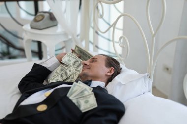 Genç iş adamı mutlu, yatakta gülümse. İşlerinde başarılı ve birçok banknot dolar parası olan insanlar. iş başarısı konsepti