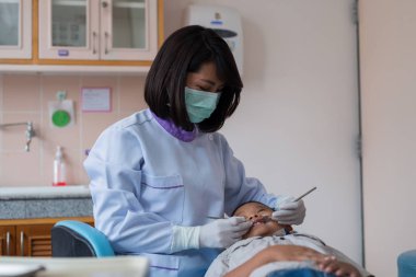 Diş hekimi diş aletini tutuyor. Hastanedeki dişçi koltuğunda yatan çocuğun dişlerini kontrol ediyorum..