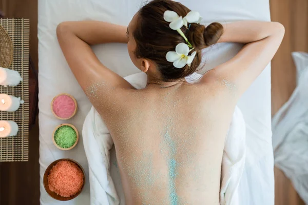 Spa masaj rahatlatıcı ve tuz fırçalama arkada masaj sahip genç güzel Asyalı kadın. sağlıklı yaşam tarzı ve gevşeme kavramı. üstten görünüm