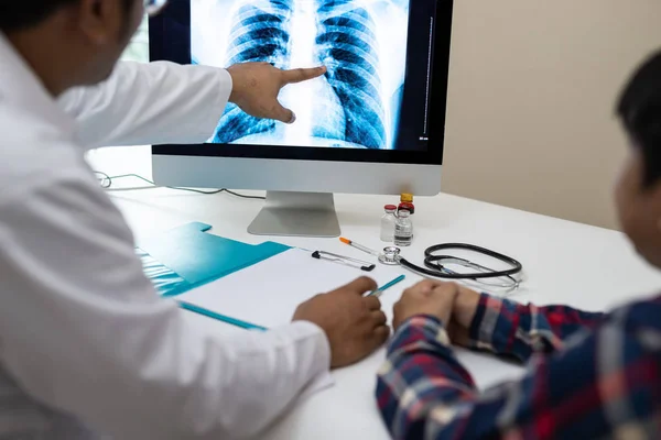 Profesyonel doktor ve onun hasta bir Danışma vererek radyolog, x-ışını bilgisayar ekranında sonuçlarına işaret etti.