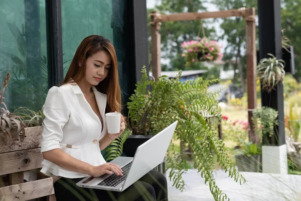 Asian young business girl drink coffee and working with laptop in coffee shop cafe