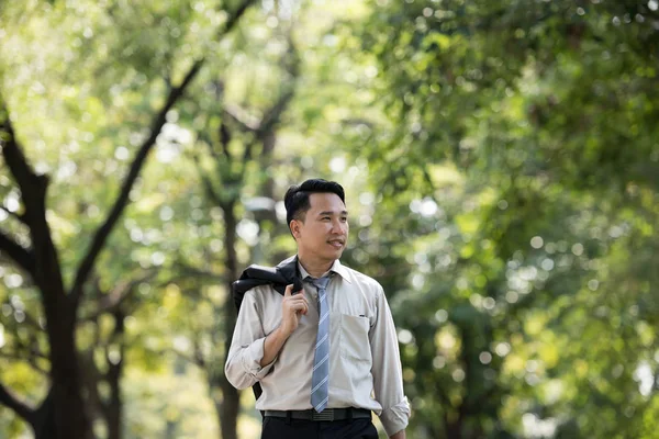 Genç Asya iş adamı gülen surat. Parkta yürüyordu..