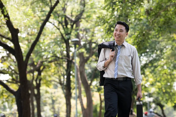 Young Asia businessman happy face. He was walking in the Park.