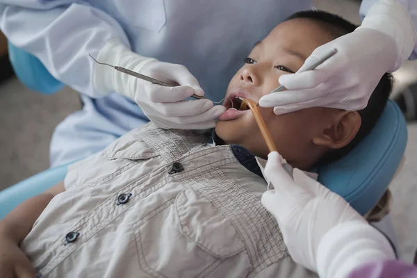 Diş hekiminin elleri diş aletini tutuyor. Hastanedeki dişçi koltuğunda yatan çocuğun dişlerini kontrol ediyorum..