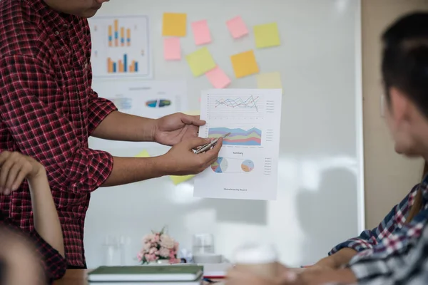 Odanın önünde dikilen sıradan ekose gömlekli genç Asyalı erkekler, konferansta başarılı bir iş yürütme konusunda meslektaşlarından geri bildirim istiyor. Takım çalışması iş toplantısı