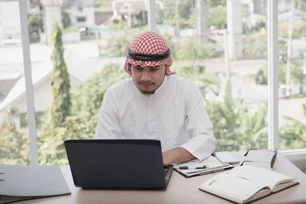 商人阿拉伯人坐在办公室的笔记本电脑旁工作 — 图库照片