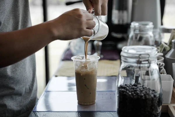 男性のバリスタが喫茶店の職場のガラスにコーヒーを注いだ アイスコーヒー — ストック写真