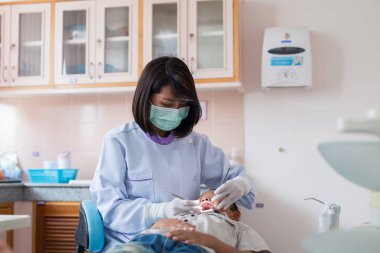 Diş hekimi diş aletini tutuyor. Hastanedeki dişçi koltuğunda yatan çocuğun dişlerini kontrol ediyorum..