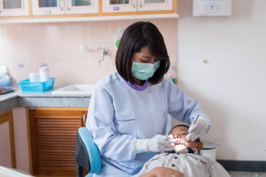 Diş hekimi diş aletini tutuyor. Hastanedeki dişçi koltuğunda yatan çocuğun dişlerini kontrol ediyorum..