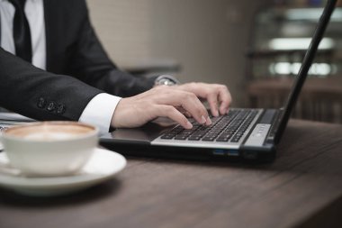 Genç Asyalı işadamı bir kafede dizüstü bilgisayarla çalışıyor..