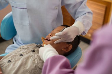 Diş hekiminin elleri diş aletini tutuyor. Hastanedeki dişçi koltuğunda yatan çocuğun dişlerini kontrol ediyorum..