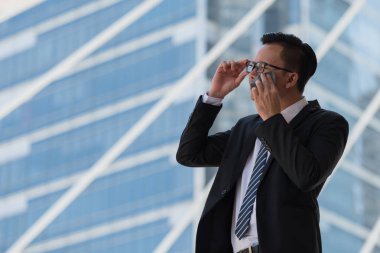 Genç Asyalı işadamı sıcak iklimden dolayı terliyor. Bangkok Tayland 'da ıslak mendil, ter ve terle yüzünü siliyor.