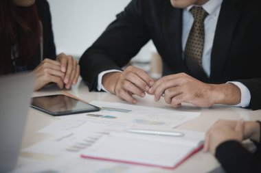 Asyalı genç iş adamları ve kadın grupları ofis masasında borsa çizelgeleri üzerinde tartışıyorlar. İş analizi yapıyorlar. Beyin fırtınası, takım çalışması, toplantı konsepti