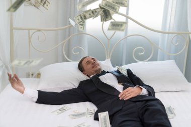 Genç iş adamı mutlu, yatakta gülümse. İşlerinde başarılı ve birçok banknot dolar parası olan insanlar. iş başarısı konsepti