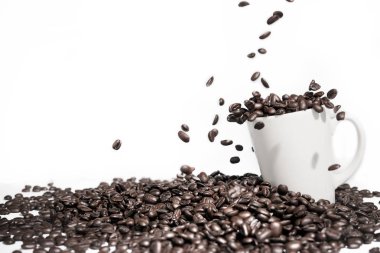 Kahve çekirdekleri cama düşer ve beyaz arka plandaki masaya yerleştirilir.