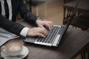 Genç Asyalı işadamı bir kafede dizüstü bilgisayarla çalışıyor..