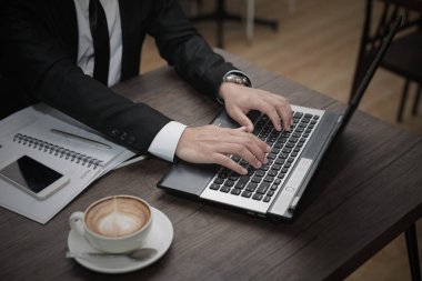 Genç Asyalı işadamı bir kafede dizüstü bilgisayarla çalışıyor..