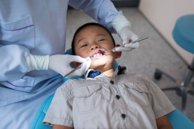 Diş hekiminin elleri diş aletini tutuyor. Hastanedeki dişçi koltuğunda yatan çocuğun dişlerini kontrol ediyorum..