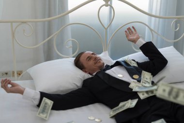 Genç iş adamı mutlu, yatakta gülümse. İşlerinde başarılı ve birçok banknot dolar parası olan insanlar. iş başarısı konsepti
