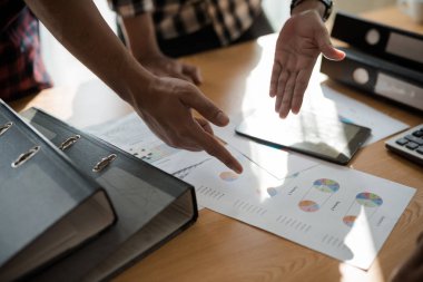 Asyalı genç iş adamları ve kadın grupları ofis masasında borsa çizelgeleri üzerinde tartışıyorlar. İş analizi yapıyorlar. Beyin fırtınası, takım çalışması, toplantı konsepti.