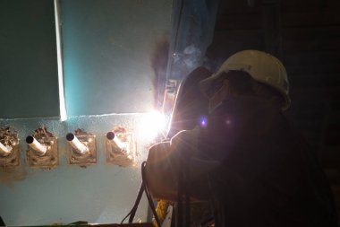 Adam kaynakçı makineleri sanayi tesisleri tam koruyucu giysi ile çalışma. Emanet kask, eldiven, Kaynak Kasklar. Emanet iş yeri kavramı