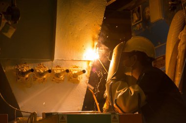 Adam kaynakçı makineleri sanayi tesisleri tam koruyucu giysi ile çalışma. Emanet kask, eldiven, Kaynak Kasklar. Emanet iş yeri kavramı