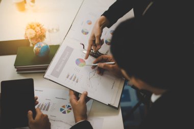 Toplantıda yapılan görüşmelerde raporlara, grafiklere, iş belgelerine işaret eden işadamı eli.