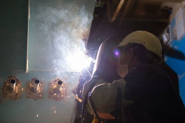 Adam kaynakçı makineleri sanayi tesisleri tam koruyucu giysi ile çalışma. Emanet kask, eldiven, Kaynak Kasklar. Emanet iş yeri kavramı