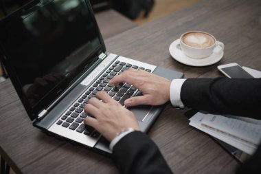 Genç Asyalı işadamı bir kafede dizüstü bilgisayarla çalışıyor..