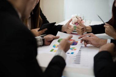 Bir grup iş adamı ve kadın iş pazarlama satış hedefinin grafiklerini görmek için bir araya geliyor. Takım çalışması iş toplantısı kavramı
