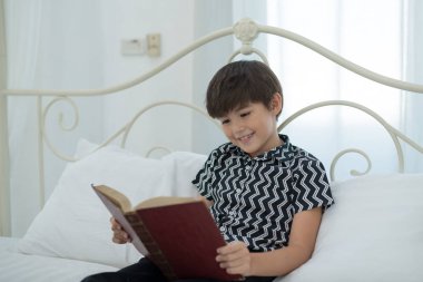 Kitap okumak çocuk gülümseyen, yatakta mutlu. eğitim kavramı