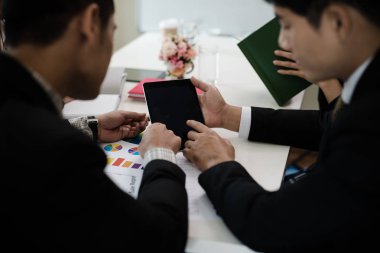 Asyalı iş adamları grubu toplanıyor. Planlamayı sunmak için dijital tablet kullanarak. Konsept Takım Çalışması