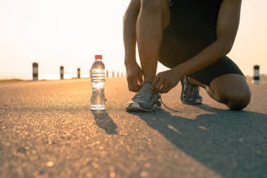 Erkek koşucu sabah ve şişe suda bir çalışma için hazırlık Ayakkabı bağlama. Sağlık ve fitness kavramı