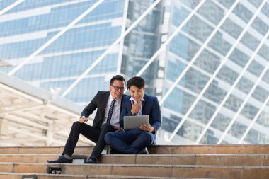 Asyalı iki işadamı dizüstü bilgisayarı izlerken mutlu oluyor. iş bölgesi arka planında