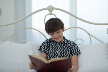 Kitap okumak çocuk gülümseyen, yatakta mutlu. eğitim kavramı