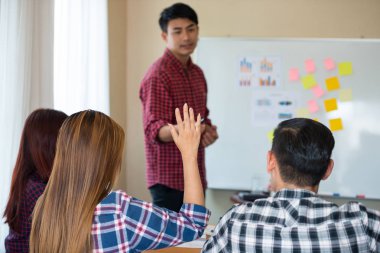 Sıradan ekose gömlek giyen Asyalı genç kadınların eli konferanstaki meslektaşlarından başarılı bir iş yürütme konusunda geri bildirim istiyor. Takım çalışması iş toplantısı