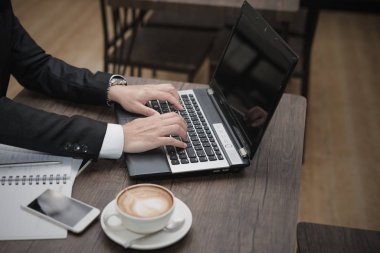 Genç Asyalı işadamı bir kafede dizüstü bilgisayarla çalışıyor..