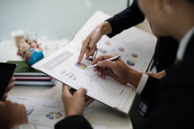 Toplantıda yapılan görüşmelerde raporlara, grafiklere, iş belgelerine işaret eden işadamı eli.