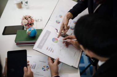 Toplantıda yapılan görüşmelerde raporlara, grafiklere, iş belgelerine işaret eden işadamı eli.