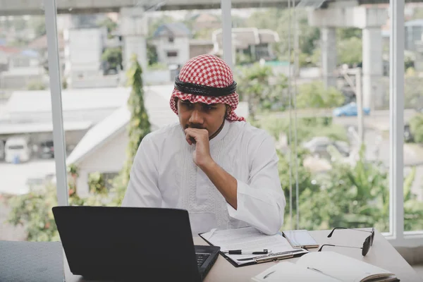 阿拉伯商人坐在那里思考着观念战略的工作概念 办公室里有笔记本电脑 — 图库照片