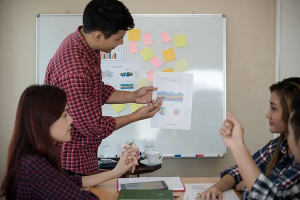 Odanın önünde dikilen sıradan ekose gömlekli genç Asyalı erkekler, konferansta başarılı bir iş yürütme konusunda meslektaşlarından geri bildirim istiyor. Takım çalışması iş toplantısı