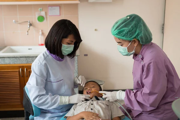 Diş hekimi diş aletini tutuyor. Hastanedeki dişçi koltuğunda yatan çocuğun dişlerini kontrol ediyorum..