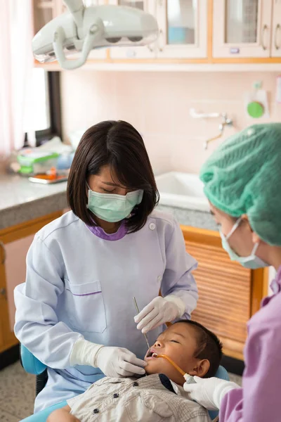 Diş hekimi diş aletini tutuyor. Hastanedeki dişçi koltuğunda yatan çocuğun dişlerini kontrol ediyorum..