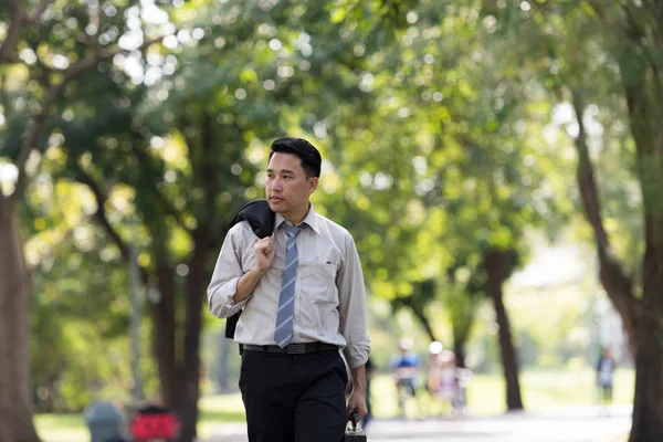 Asyalı genç iş adamı stres yapıyor. Parkta yürüyordu..