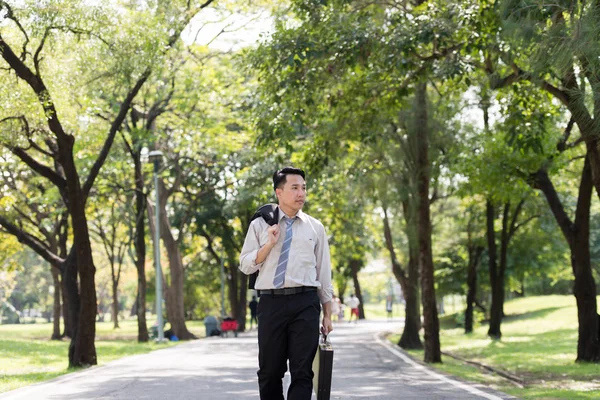 Asyalı genç iş adamı stres yapıyor. Parkta yürüyordu..