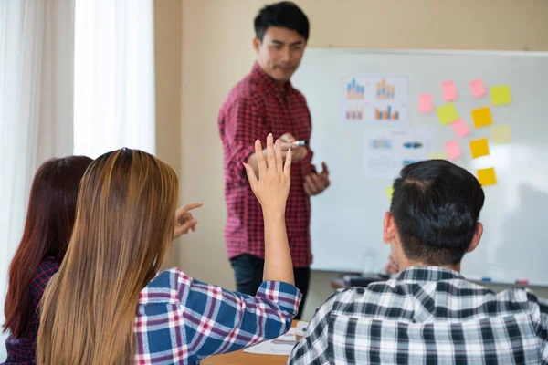 Sıradan ekose gömlek giyen Asyalı genç kadınların eli konferanstaki meslektaşlarından başarılı bir iş yürütme konusunda geri bildirim istiyor. Takım çalışması iş toplantısı