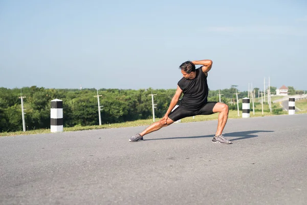 Erkek koşucu sabah koşuya hazırlanmak için bacak kasları germe. Sağlık ve fitness kavramı