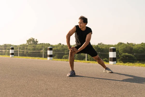 Erkek koşucu sabah koşuya hazırlanmak için bacak kasları germe. Sağlık ve fitness kavramı
